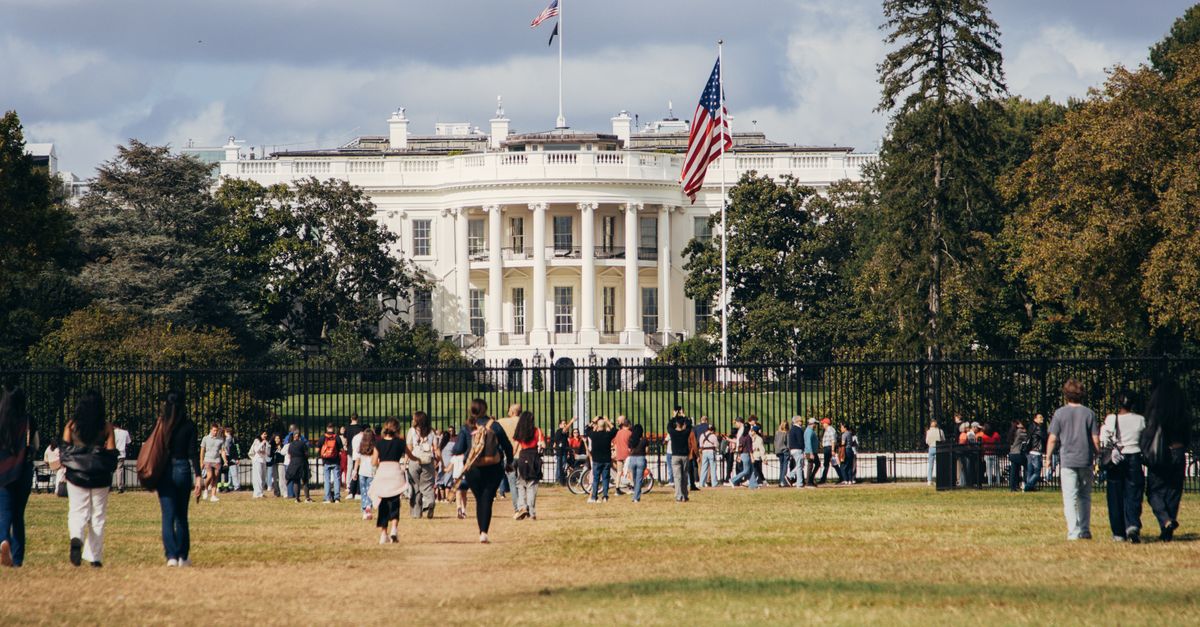 Tourists gather outside the White House on a sunny day, capturing the landmark's grandeur.